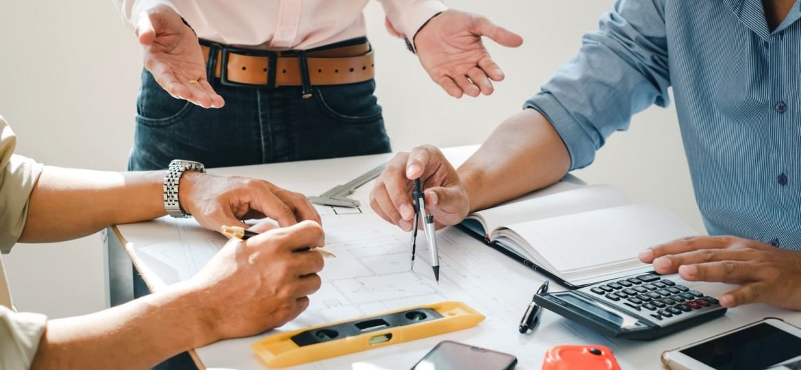 Engineer and contractor planning projects together at desk with